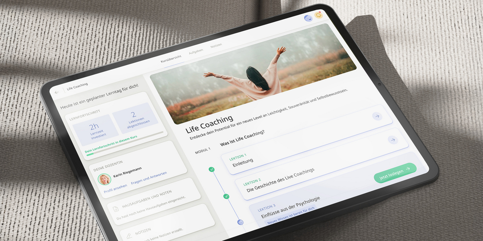 Tablet mit deutschem Onlinekurs "Life Coaching". Bild: Person hebt Arme. Zu sehen: Lektionen, Trainerinfos, Fortschritt.